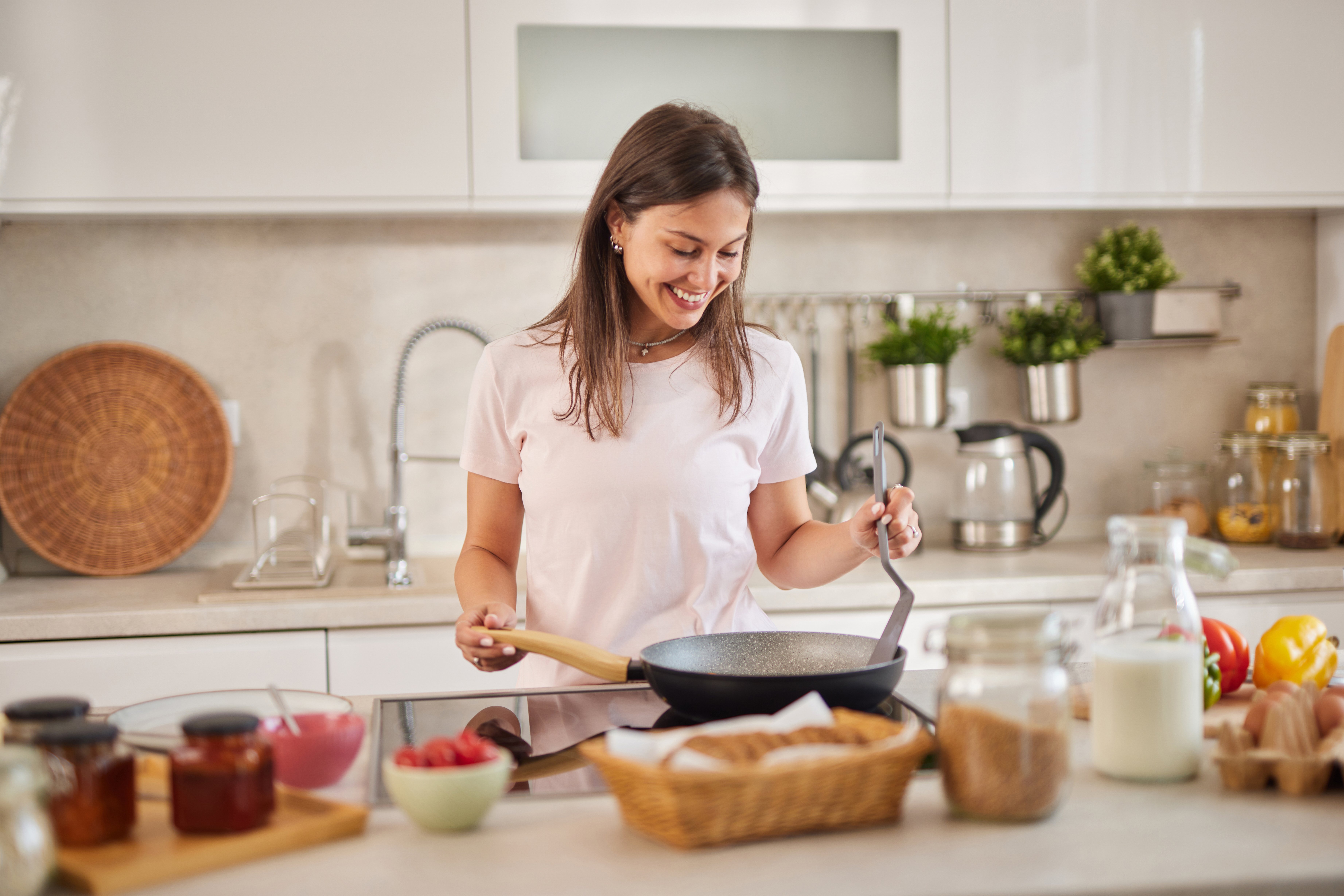 Happy young woman cooking breakfast in a modern kitchen, enjoying her morning routine